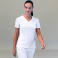Modelo caminando con filipina quirúrgica blanca 530 para mujer y pantalón blanco, vista frontal.