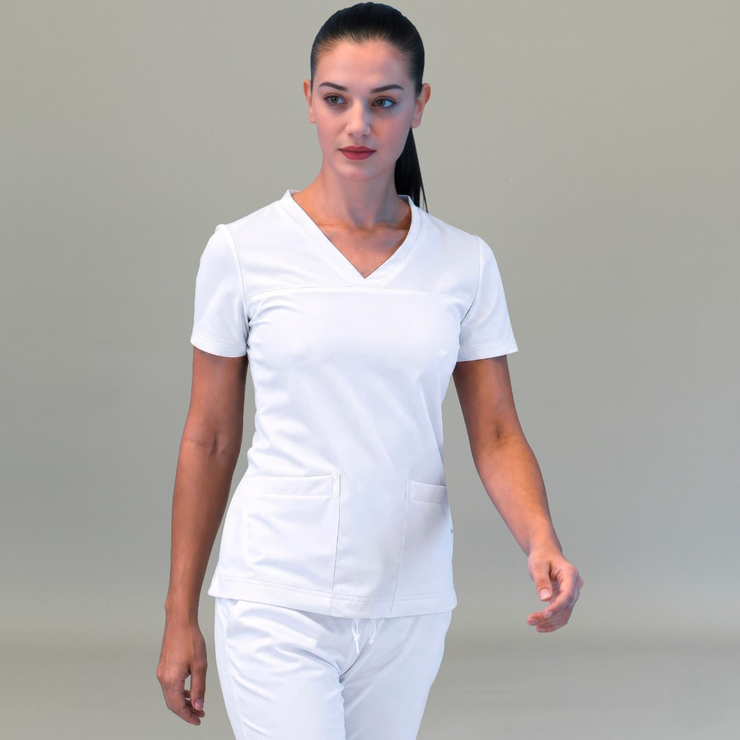 Modelo caminando con filipina quirúrgica blanca 530 para mujer y pantalón blanco, vista frontal.