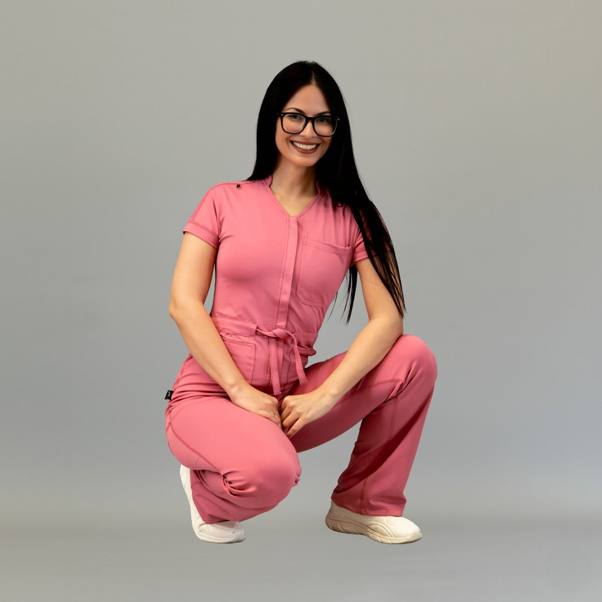 Modelo agachada con jumpsuit Super Stretch Palo de Rosa para mujer